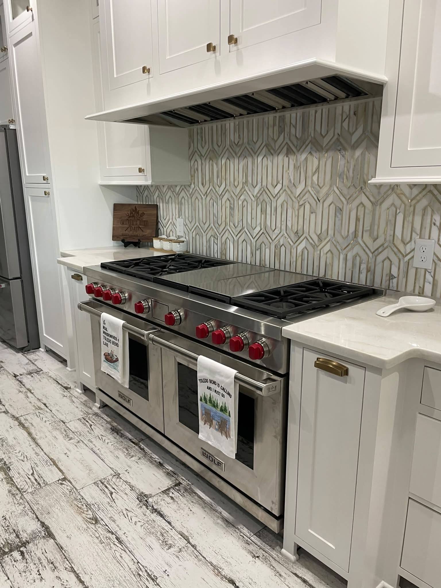 Custom kitchen with a painted hood surround, professional range and chevron-patterned marble backsplash