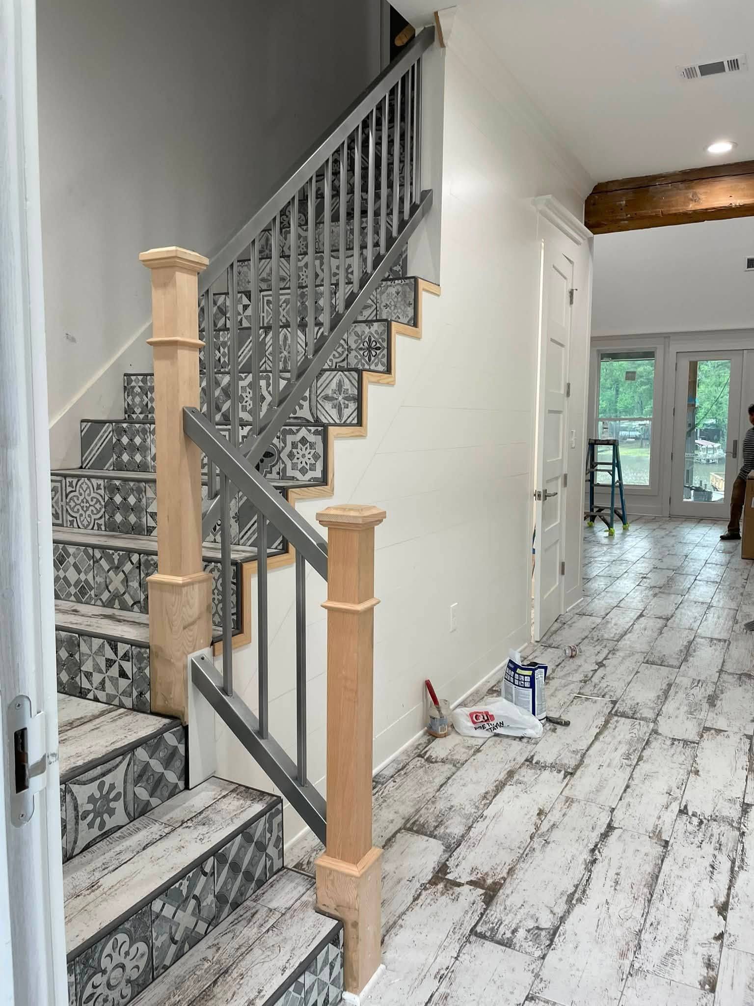 Custom staircase with square newel posts, a painted balustrade and patterned tile risers