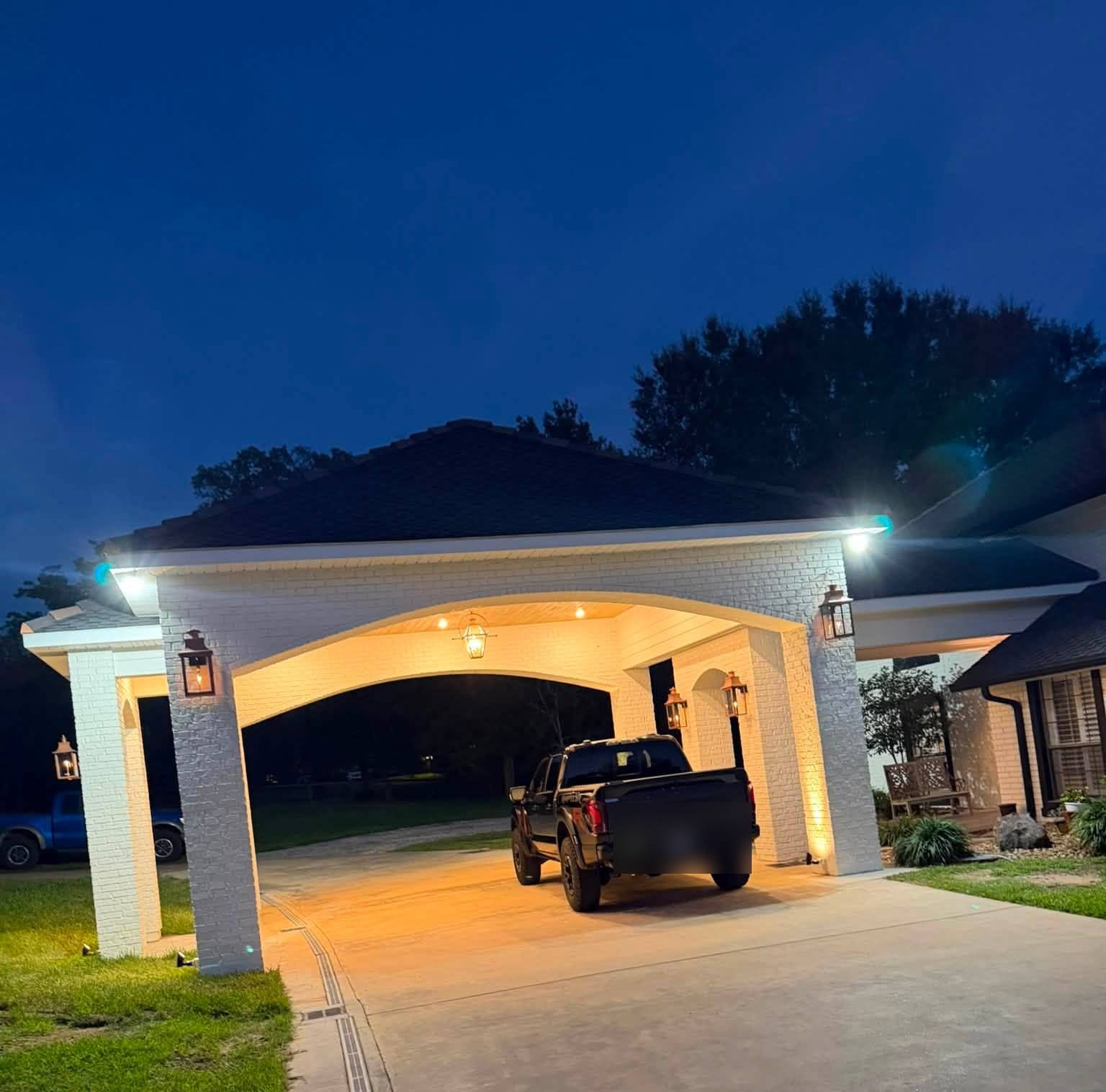 Painted brick porte-cochere lit by copper gas lanterns at dusk